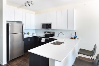 A modern kitchen with a white countertop and black cabinets at Two Twelve Clayton Apartments, Clayton 63105